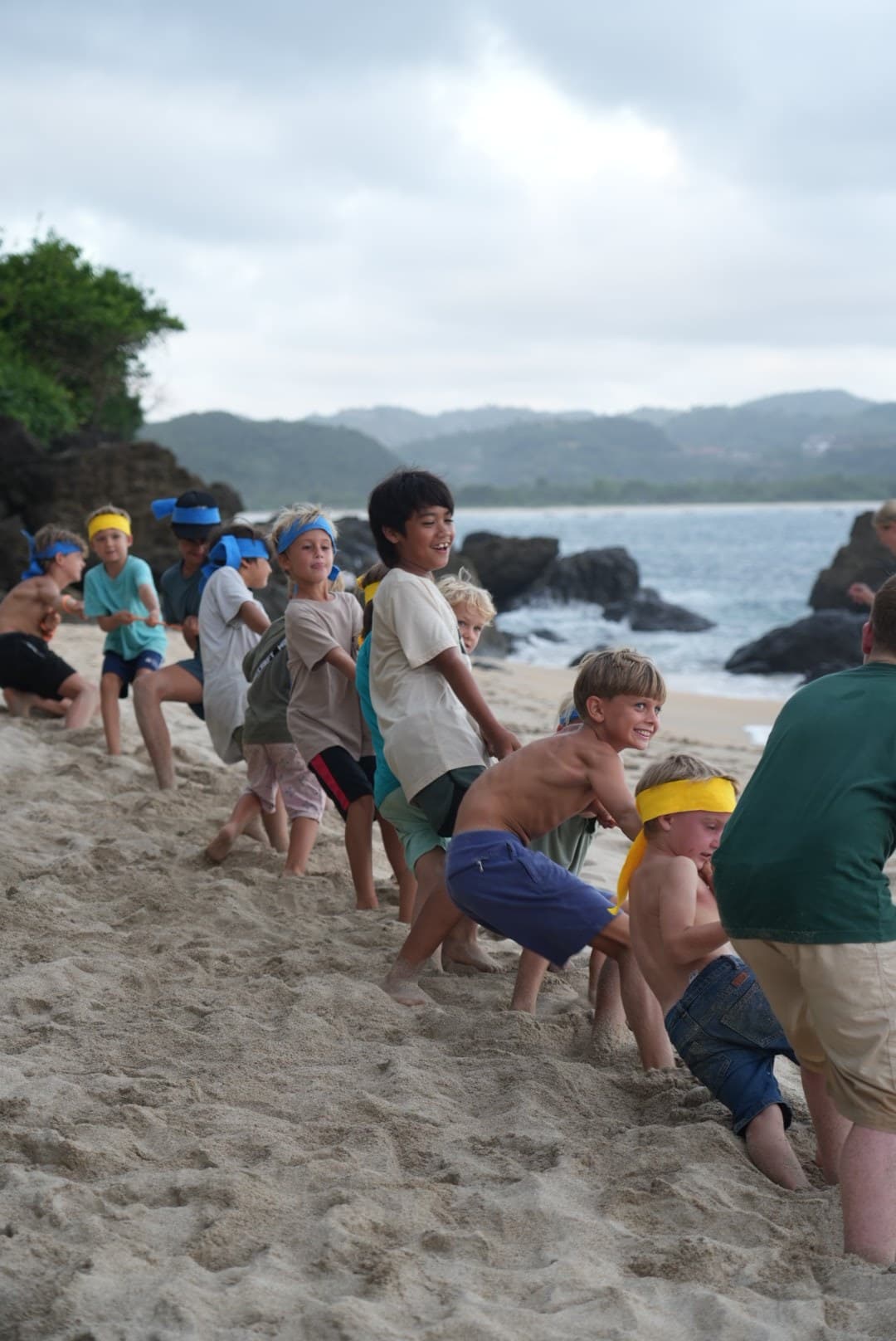 Students playing tug of war together on the beach at Selong Belanak